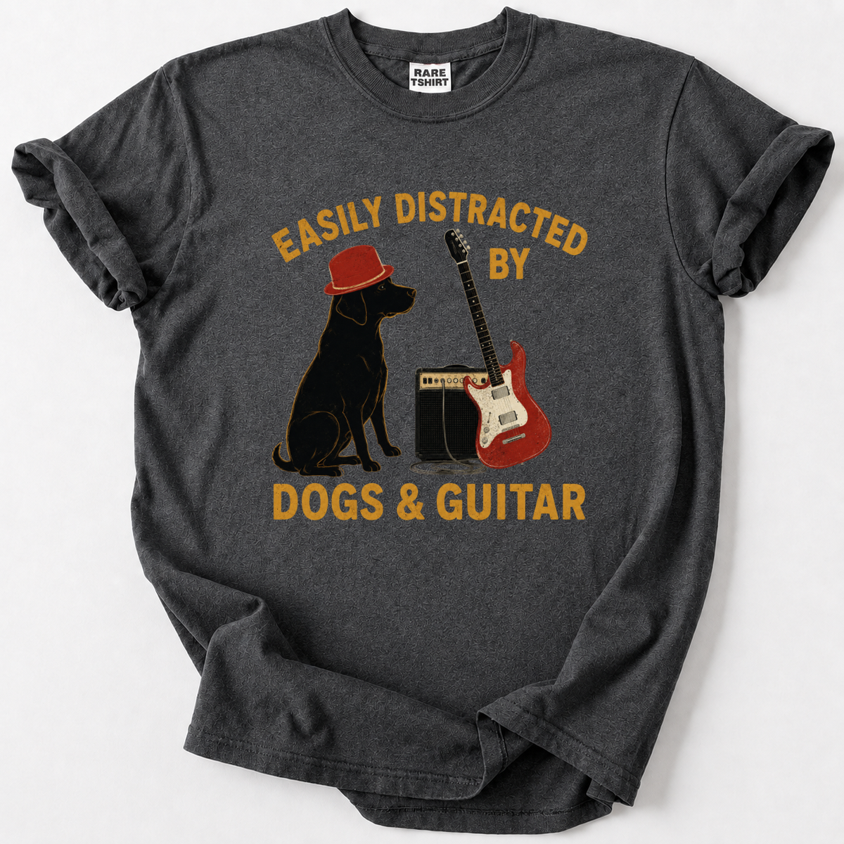 A dark gray heather t-shirt with a graphic print of a black dog wearing a red hat, a red electric guitar, and a speaker, with the text 'EASILY DISTRACTED BY DOGS & GUITAR' in yellow. The shirt is laid flat on a light gray background.