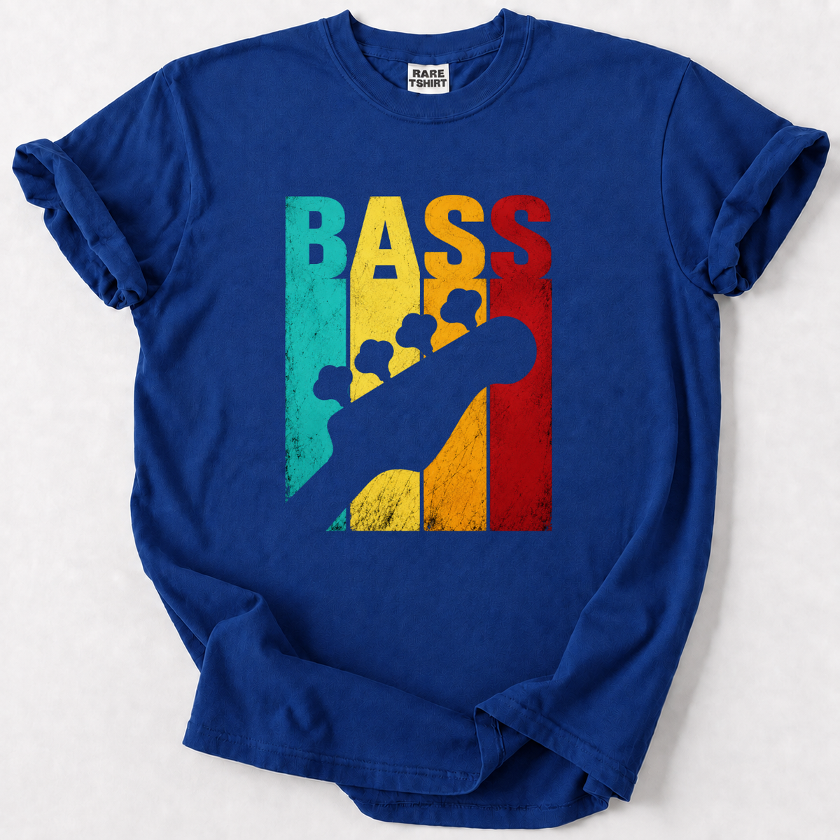 A royal blue short-sleeve t-shirt with a graphic print on the front. The graphic features the word 'BASS' in large, distressed vertical letters colored teal, yellow, and red, overlaid with a dark blue silhouette of a bass guitar.